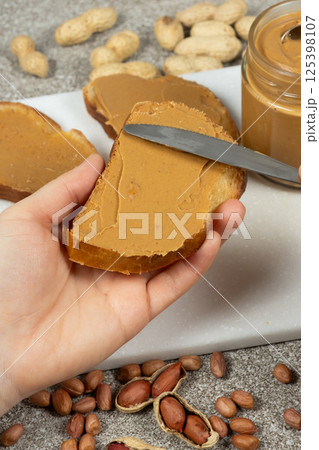 The process of spreading peanut butter on bread, hands close-up 125398107