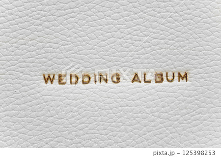 The inscription Wedding Album in gold letters on the white leather cover of book 125398253