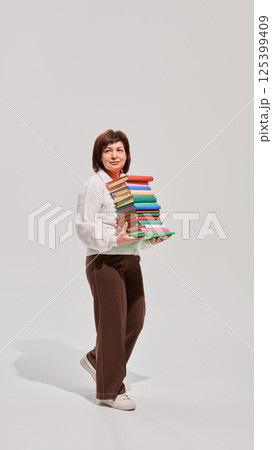 Senior woman holding book above head 125399409