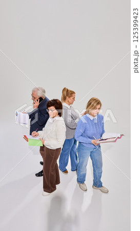 View from above on four elderly people, students involved in learning session, standing with books, studying against white background. 125399423