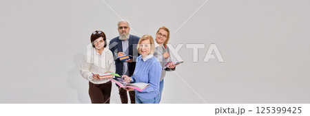 Positive elderly people, man and woman standing with books and notes against white background. representing special educational courses for seniors. 125399425