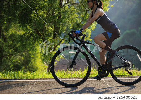 Woman cyclist riding bike in summer park 125400623