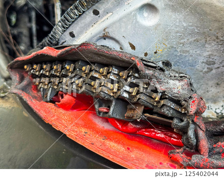 Close-up of a severely burned LED tail light module from a car, showing melted plastic housing, exposed electrical components, and heat-damaged internal structure 125402044