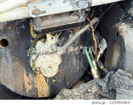 Burned air conditioning compressor valve from a car showing heat damage, melted sealing material, exposed copper wiring, and connected refrigerant lines Burned air conditioning compressor valve from a car showing heat damage, melted sealing material, exposed copper wiring, and connected refrigerant lines 125402064