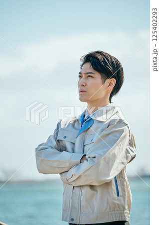 遠くを見つめる作業着姿の20代の若い男性 遠くを見つめる作業着姿の20代の若い男性 125402293