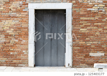 Old Metal Door in Brick Wall with Stone Frame 125403177