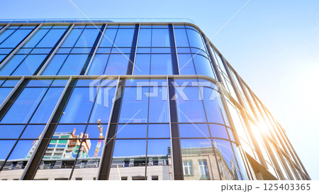 Modern office building with glass facade on a clear sky background. Transparent glass wall of office building. Modern office building with glass facade on a clear sky background. Transparent glass wall of office building. 125403365