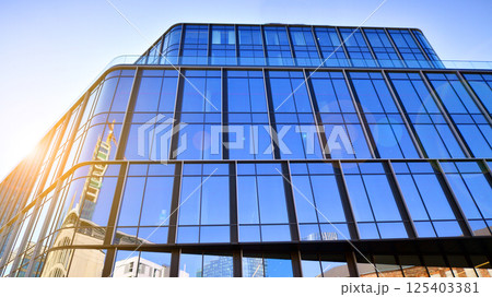Modern office building with glass facade on a clear sky background. Transparent glass wall of office building. 125403381