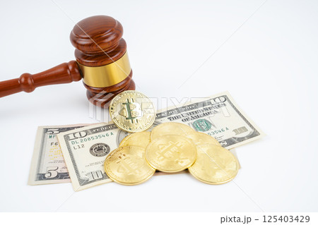 Judge gavel and bitcoins with USD banknotes on white. 125403429