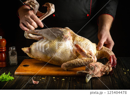 A chef prepares a whole turkey on a wooden cutting board, seasoning it with spices. The setting is a well-equipped kitchen, highlighting culinary skills and food preparation techniques A chef prepares a whole turkey on a wooden cutting board, seasoning it with spices. The setting is a well-equipped kitchen, highlighting culinary skills and food preparation techniques 125404478