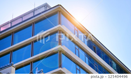 Downtown corporate business district architecture. Glass reflective office buildings against blue sky and sun light. Economy, finances, business activity concept. Rising sun on the horizon. 125404496