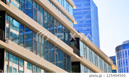 Downtown corporate business district architecture. Glass reflective office buildings against blue sky and sun light. Economy, finances, business activity concept. Rising sun on the horizon. 125404505