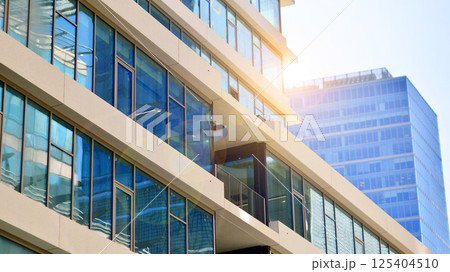 Downtown corporate business district architecture. Glass reflective office buildings against blue sky and sun light. Economy, finances, business activity concept. Rising sun on the horizon. 125404510