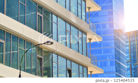 Downtown corporate business district architecture. Glass reflective office buildings against blue sky and sun light. Economy, finances, business activity concept. Rising sun on the horizon. 125404515