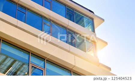 Downtown corporate business district architecture. Glass reflective office buildings against blue sky and sun light. Economy, finances, business activity concept. Rising sun on the horizon. 125404523