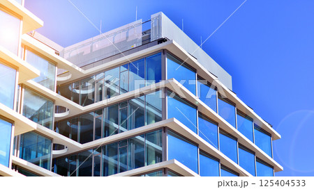 Downtown corporate business district architecture. Glass reflective office buildings against blue sky and sun light. Economy, finances, business activity concept. Rising sun on the horizon. Downtown corporate business district architecture. Glass reflective office buildings against blue sky and sun light. Economy, finances, business activity concept. Rising sun on the horizon. 125404533