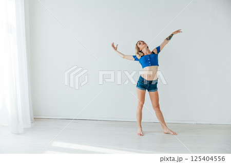 Blonde dancing to music alone in a room with a window Blonde dancing to music alone in a room with a window 125404556
