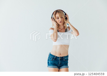 Blonde woman listening to music in headphones and dancing 125404559