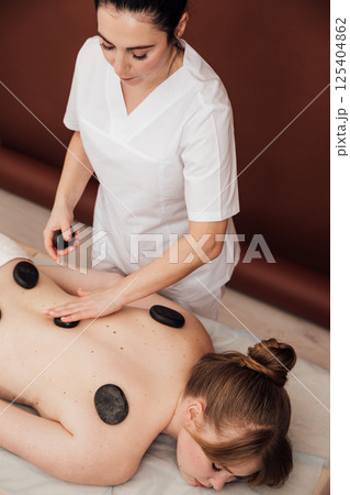 Woman on table at masseur on back massage in spa Woman on table at masseur on back massage in spa 125404862