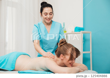 Woman on table at masseur on back massage in spa 125404866
