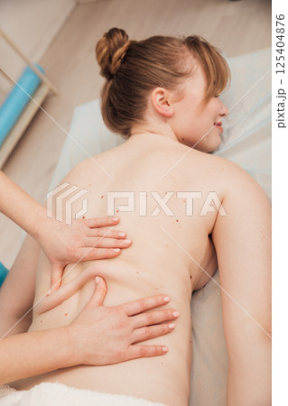 Woman massage therapist doing relaxing medical back massage in spa 125404876