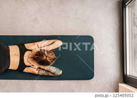 Woman Practicing Yoga in Puppy Pose Variation Woman Practicing Yoga in Puppy Pose Variation 125405052