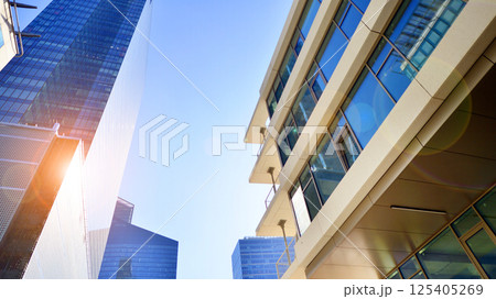 Downtown corporate business district architecture. Glass reflective office buildings against blue sky and sun light. Economy, finances, business activity concept. Rising sun on the horizon. 125405269