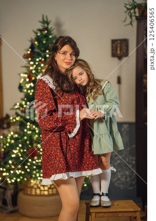 Beautiful mother and daughter at the Christmas tree. Beautiful mother and daughter at the Christmas tree. 125406565