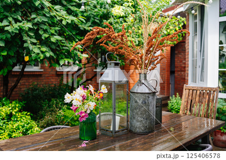 wooden table with lanterns and dried flowers. The yard in the house. 125406578
