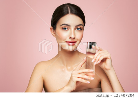 Smiling woman holds bottle with cosmetic tonic Smiling woman holds bottle with cosmetic tonic 125407204