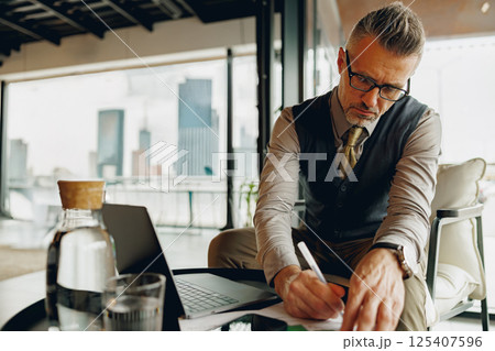 A Professional Man Working Diligently in a Modern Office with an Impressive City View A Professional Man Working Diligently in a Modern Office with an Impressive City View 125407596