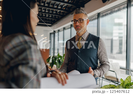 A Professional Business Meeting featuring Detailed Project Plans in a Modern Office Environment A Professional Business Meeting featuring Detailed Project Plans in a Modern Office Environment 125407612