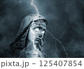 Statue of the sacred virgin Mary with glowing eyes struck by lightning in a stormy sky 125407854