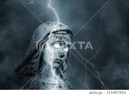 Statue of the sacred virgin Mary with glowing eyes struck by lightning in a stormy sky 125407854