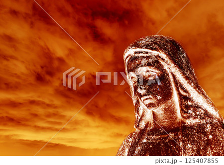 Crying statue of the virgin Mary against a burning sky Crying statue of the virgin Mary against a burning sky 125407855