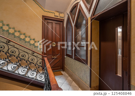 Elegant stairway with ornate wrought iron railings and wooden doors in a classic interior 125408846