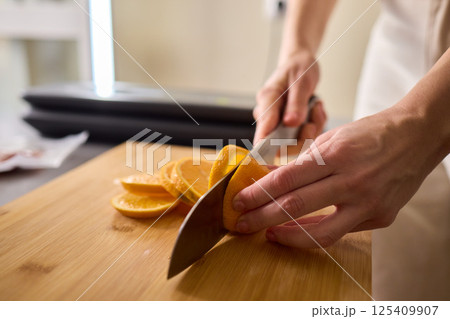 Slicing Fresh Oranges on a Beautiful Wooden Cutting Board to Enhance Your Culinary Skills 125409907