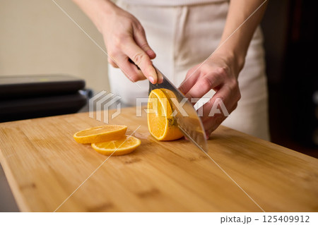 Slicing Fresh Oranges on a Beautiful Wooden Cutting Board to Enhance Your Culinary Skills Slicing Fresh Oranges on a Beautiful Wooden Cutting Board to Enhance Your Culinary Skills 125409912