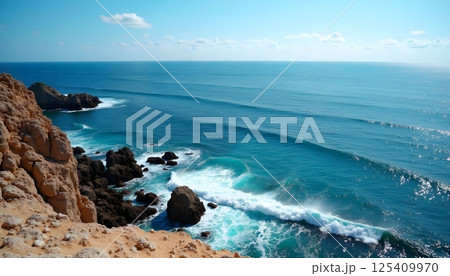 This photograph captures a breathtaking coastal landscape where rugged cliffs meet the vibrant blue ocean. The foreground showcases golden-brown rocky cliffs and boulders/ 125409970