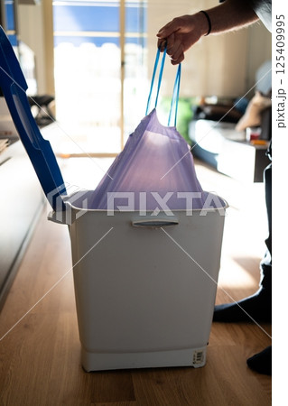 A man takes out a trash bag from a bin. Maintaining cleanliness and household cleaning A man takes out a trash bag from a bin. Maintaining cleanliness and household cleaning 125409995