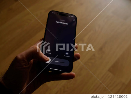 Fraud or fraudulent schemes. Close-up of a male hand holding a phone with an unexpected incoming call from an unknown Fraud or fraudulent schemes. Close-up of a male hand holding a phone with an unexpected incoming call from an unknown 125410001
