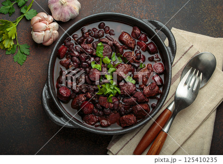 Brazilian feijoada with black beans, sausage, and meat in a pot, top view Brazilian feijoada with black beans, sausage, and meat in a pot, top view 125410235