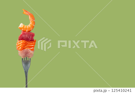 Diverse protein sources on a fork, pieces of raw salmon, beef, chicken and shrimp on green background, space for text 125410241