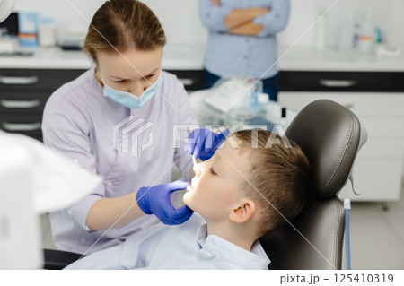 Female dentist examining teeth of child patient in dental clinic Female dentist examining teeth of child patient in dental clinic 125410319