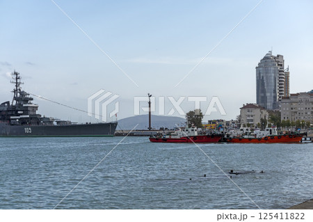 Novorossiysk, Russia - 18 August 2023. Cruiser Mikhail Kutuzov and dolphins, Black Sea, port, Krasnodar Territory, Novorossiysk. Novorossiysk, Russia - 18 August 2023. Cruiser Mikhail Kutuzov and dolphins, Black Sea, port, Krasnodar Territory, Novorossiysk. 125411822