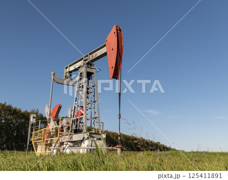 Operating oil and gas well in oil field, profiled against the blue sky Operating oil and gas well in oil field, profiled against the blue sky 125411891