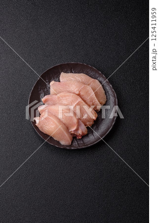 Raw chicken or turkey fillet cut into slices with salt, spices and herbs Raw chicken or turkey fillet cut into slices with salt, spices and herbs 125411959