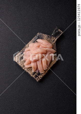 Raw chicken or turkey fillet cut into slices with salt, spices and herbs Raw chicken or turkey fillet cut into slices with salt, spices and herbs 125411974