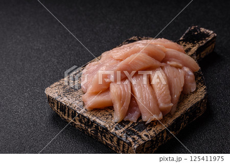 Raw chicken or turkey fillet cut into slices with salt, spices and herbs Raw chicken or turkey fillet cut into slices with salt, spices and herbs 125411975