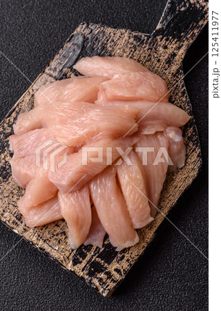 Raw chicken or turkey fillet cut into slices with salt, spices and herbs 125411977